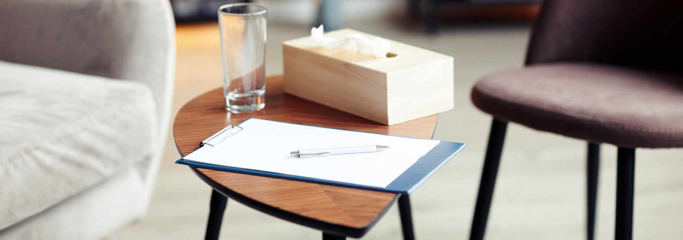 Therapist office with chairs, table, glass, notebook, pen, tissues